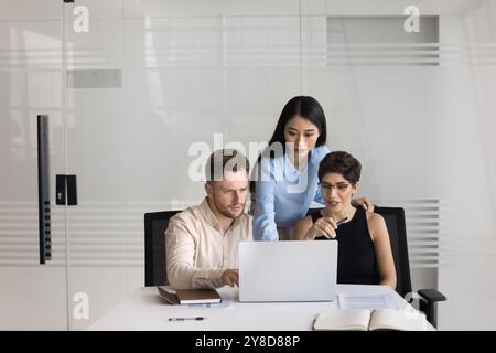 Kleines, vielfältiges Business-Team aus drei Kollegen, das sich am Laptop trifft Stockfoto