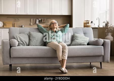 Ältere Frau sitzt bequem auf dem Sofa im modernen Wohnzimmer Stockfoto
