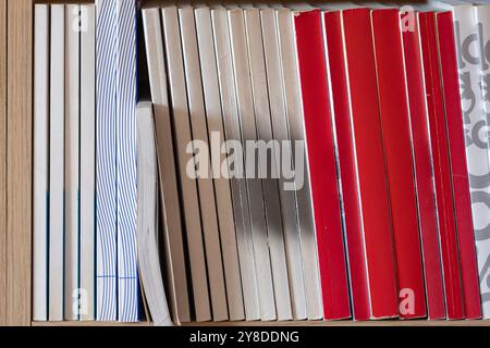 Organisierte Sammlung von Büchern auf einem hölzernen Bücherregal. Bücher, die ordentlich in einem Regal angeordnet sind, mit einer Vielzahl von Farben und Texturen, ideal für Präsentationen Stockfoto