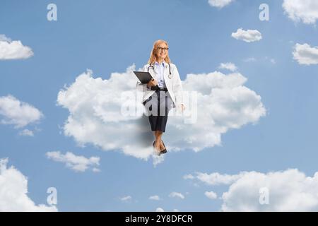 Ärztin lächelt und sitzt auf einer Wolke am Himmel Stockfoto