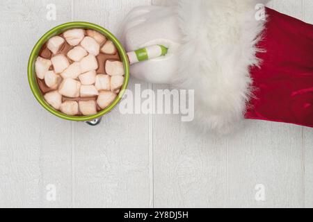Nahaufnahme der Hand des Weihnachtsmanns, die nach heißer Schokolade greift Stockfoto