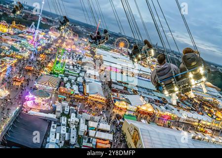 Die Wiesn leuchtet, Blick vom Kettenflieger Bayern Tower auf das Oktoberfest, Abends, München, Oktober 2024 Deutschland, München, 4. Oktober 2024, Wiesnbesucher genießen den Flug durch den Münchner Himmel, in 90 Metern Höhe haben sie einen wunderbaren Blick über das Oktoberfest, abends in der Blauen Stunde, direkt nach Sonnenuntergang um 18:50 Uhr, Kettenflieger Bayern Tower, 90 Meter hohes Kettenkarussell, Theresienwiese, Fahrgeschäft gehört Schausteller Egon Kaiser, Freitagabend, Himmel bewölkt, Wochenende, Wiesnwetter, bayerisch, Volksfest, Herbst, Bayern, *** die Wiesn leuchtet auf, Blick auf den Stockfoto