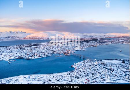 Aus der Vogelperspektive von Tromso, Norwegen bei Sonnenuntergang im Winter vom Storsteinen Berg. Tromsoya Insel mit schneebedeckten Dächern der Innenstadt von Tromso, Hafen Stockfoto
