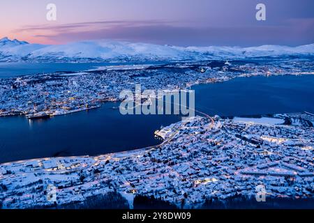 Aus der Vogelperspektive von Tromso, Norwegen, mit Lichtern der Stadt im Winter vom Storsteinen Berg in der Dämmerung. Tromsoya Insel mit Tromso Innenstadt, Hafen Stockfoto