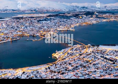 Aus der Vogelperspektive von Tromso, Norwegen, mit Lichtern der Stadt im Winter vom Storsteinen Berg. Tromsoya Insel mit schneebedeckten Dächern der Stadt Tromso, Hafen Stockfoto