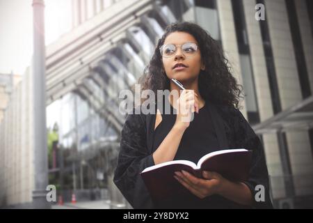 Selbstständige Unternehmerin mit gemischter Rasse, die in ihrem Notizbuch schreibt Stockfoto
