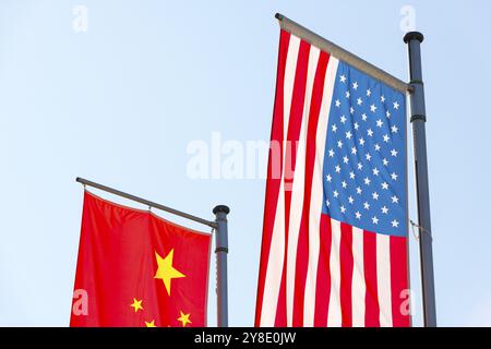 Verschiedene Nationalflaggen fliegen auf Fahnenmasten vor blauem Himmel, chinesische Flagge, amerikanische Flagge Stockfoto