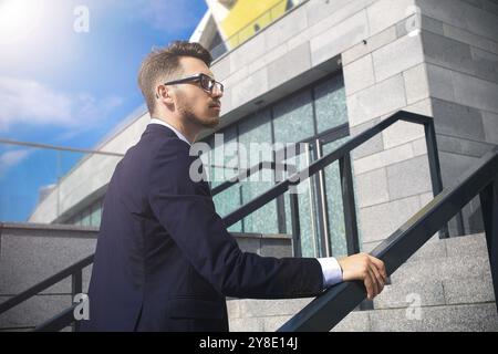 Hübscher erfolgreicher Geschäftsmann in elegantem Anzug im Freien, der auf der Straße in der Stadt spaziert Stockfoto