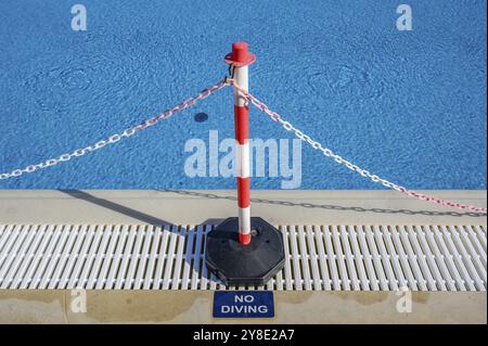 Absperrkette ohne Tauchschild am Rand eines blauen Schwimmbades Stockfoto