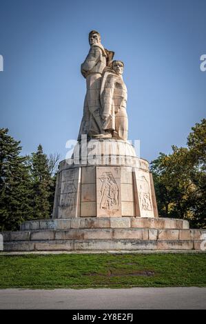 Eine detaillierte Steinskulptur (Pantheon Varna) mit Reliefs, die vor einem klaren blauen Himmel stehen, Varna, Bulgarien, Europa Stockfoto