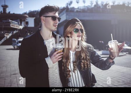 Niedliches Paar, das Spaß hat, auf der Straße zu spazieren und Cocktails zu trinken, guter Tag Stockfoto