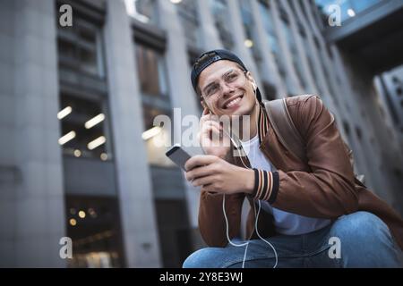 Man Sitzt Und Hört Musik-Kopfhörer-Konzept. Fröhlicher junger Kerl, der die Musik hört Stockfoto
