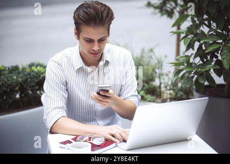 Intelligente Einstellung. Positiv aussehender Mann, der einen Laptop benutzt und im Café sitzt, während er im Internet surft Stockfoto