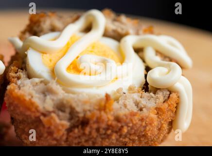 Frisch arrangierter, verzehrfertiger Mittagssnack mit Tomatenscheiben, auf einem hölzernen Schneidebrett mit Details von Gebäckbröseln und Texturen des Essens. Stockfoto