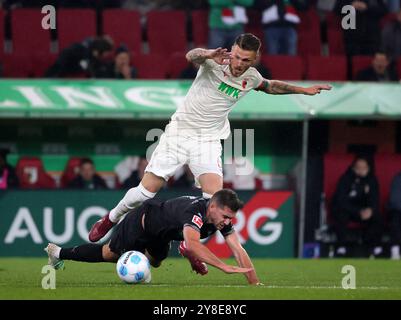 Augsburg, Deutschland. Oktober 2024. Jeffrey Gouweleeuw (Top) von Augsburg streitet mit Kevin Stoeger von Mönchengladbach während des ersten Bundesliga-Fußballspiels zwischen dem FC Augsburg und Borussia Mönchengladbach in Augsburg, Deutschland, 4. Oktober 2024. Quelle: Philippe Ruiz/Xinhua/Alamy Live News Stockfoto