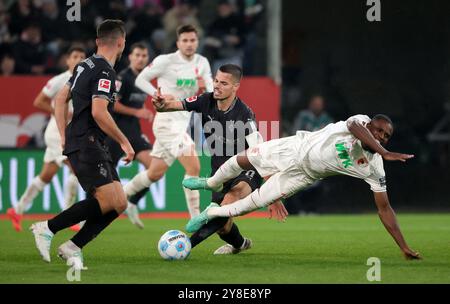 Augsburg, Deutschland. Oktober 2024. Frank Onyeka (R) aus Augsburg fällt während des Fußballspiels der Bundesliga zwischen dem FC Augsburg und Borussia Mönchengladbach am 4. Oktober 2024 in Augsburg. Quelle: Philippe Ruiz/Xinhua/Alamy Live News Stockfoto