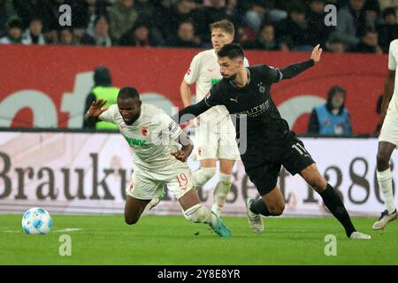 Augsburg, Deutschland. Oktober 2024. Frank Onyeka (L) aus Augsburg wird von Tim Kleindienst aus Mönchengladbach beim Fußball-Erstligisten-Spiel zwischen dem FC Augsburg und Borussia Mönchengladbach am 4. Oktober 2024 in Augsburg angegriffen. Quelle: Philippe Ruiz/Xinhua/Alamy Live News Stockfoto