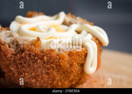 Frisch arrangierter, verzehrfertiger Mittagssnack mit Tomatenscheiben, auf einem hölzernen Schneidebrett mit Details von Gebäckbröseln und Texturen des Essens. Stockfoto