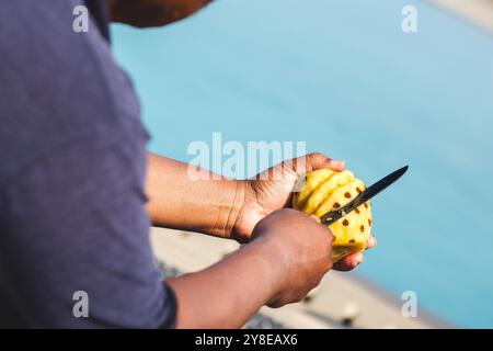 Mann, der Ananas mit Messer schneidet. Vom ganzen in die Schichten. Stockfoto