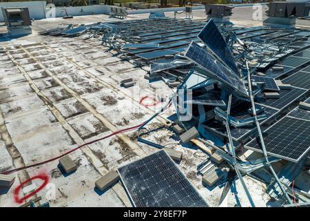 Draufsicht der durch den Hurrikan Ian zerstörten Photovoltaik-Solarpaneele, die auf dem Dach des Industriebaues zur Erzeugung von ökologischem Strom montiert sind. Konse Stockfoto