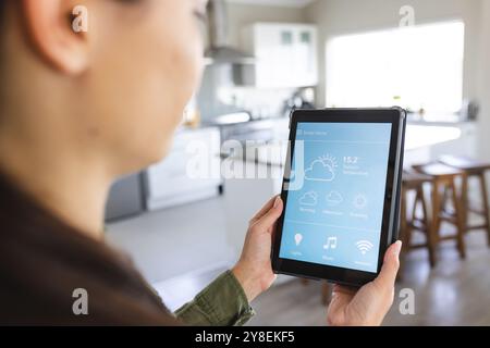 Mittelteil einer jungen kaukasischen Frau, die ein digitales Tablet benutzt und Smart Home, Kopierraum steuert Stockfoto