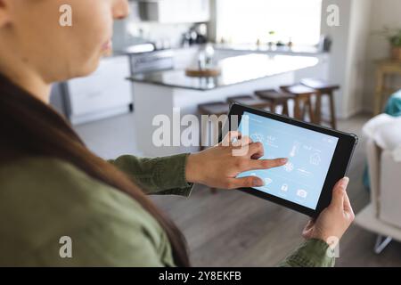 Mittelteil der jungen kaukasischen Frau, die Smart Home über ein digitales Tablet, Kopierraum steuert Stockfoto