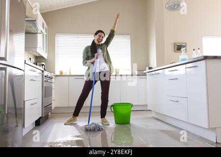 Fröhliche weiße junge Frau mit handgewachsenem Tanz, Gesang und Putzboden mit nassem Mopp Stockfoto