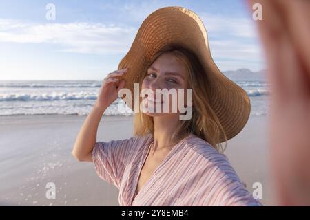 Weiße Frau mit Hut, die ein Selfie am Strand macht Stockfoto