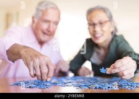 Glückliches Seniorenpaar, das am Tisch sitzt und Puzzles macht Stockfoto