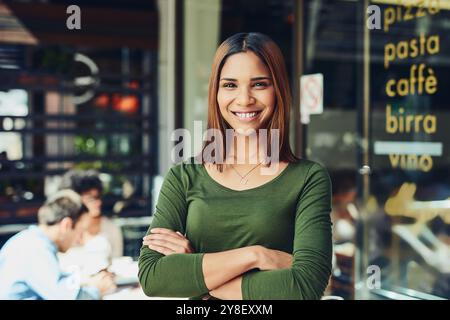 Frau, Porträt oder selbstbewusst im Restaurant für kleine Unternehmen, glücklich oder stolz auf die Stadt. Unternehmer, Lächeln oder Arme in der Cafeteria zum Willkommen Stockfoto