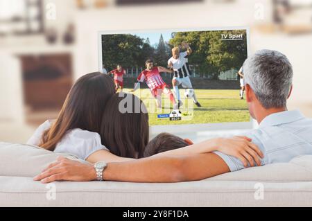 Fußballspieler tritt gegen die Familie und schaut gemeinsam auf dem Sofa Fernsehen Stockfoto