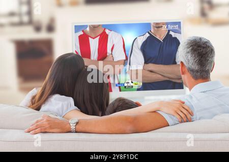 Fußballspieler tritt gegen die Familie und schaut gemeinsam auf dem Sofa Fernsehen Stockfoto