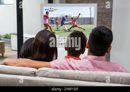 Rückansicht einer glücklichen Familie, die auf dem Sofa Fernsehen sah Stockfoto