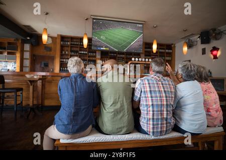 Eine Gruppe von Senioren, die sich das Fußballspiel anschauen, sitzen zusammen in der Bar. Sport, Wettkampf und Beifall. Stockfoto