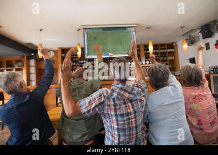 Glückliche Gruppe von Senioren, die sich das Fußballspiel anschauen, sitzen zusammen in der Bar. Sport, Wettkampf und Beifall. Stockfoto