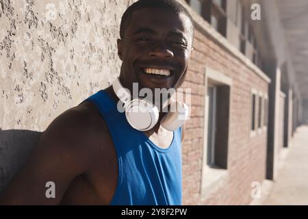 Porträt eines lächelnden afroamerikanischen Mannes, der draußen trainiert und Kopfhörer trägt Stockfoto