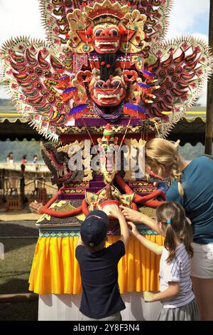 Frauen und Kinder Touristen, die auf eine traditionelle, skulpturale Kunst aus Reismehl (Opfergabe für spirituelle Zeremonie) in Bali, Indonesien, achten. Stockfoto