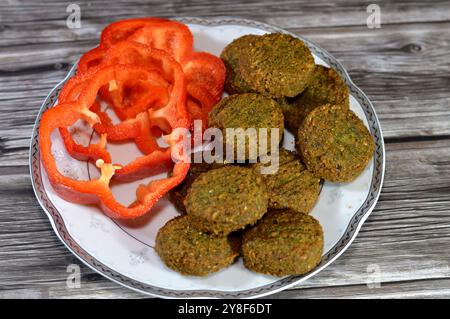 Scheiben farbiger Paprika und traditionelle ägyptische frittierte Falafelbällchen, grüner Burger, hergestellt aus gemahlenen Kichererbsen und breiten Bohnen, frittierte Bällchen Stockfoto