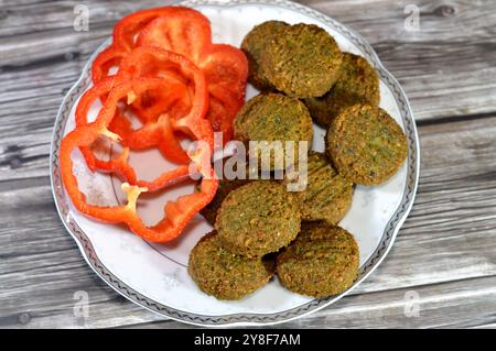 Scheiben farbiger Paprika und traditionelle ägyptische frittierte Falafelbällchen, grüner Burger, hergestellt aus gemahlenen Kichererbsen und breiten Bohnen, frittierte Bällchen Stockfoto