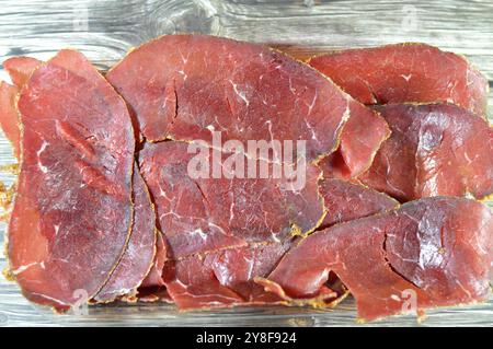 Dünne Scheiben Rindfleisch-Pastrami, aus Rinderbrust hergestellt, rohes Fleisch wird gebraten, teilweise getrocknet, mit Kräutern und Gewürzen gewürzt, dann geräuchert und gedünstet, li Stockfoto