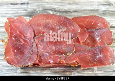 Dünne Scheiben Rindfleisch-Pastrami, aus Rinderbrust hergestellt, rohes Fleisch wird gebraten, teilweise getrocknet, mit Kräutern und Gewürzen gewürzt, dann geräuchert und gedünstet, li Stockfoto