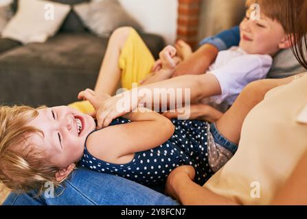 Kinder, lachen und spielen zu Hause für Bindungen, Unterstützung und Wochenende mit Liebe, Sorgfalt und Kitzeln. Mutter, Geschwister und Leute in Familienwohnung Stockfoto