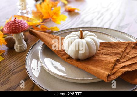 Herbst, Herbst, Halloween oder Thanksgiving festliche Tischdekoration. Gefallene Blätter, Kürbisse und Servietten auf Teller auf Holztischhintergrund. Stockfoto