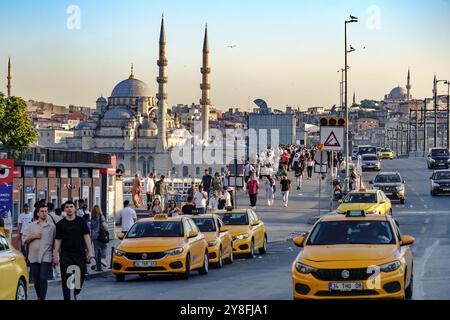 Turkiye. Istanbul. Menschenmenge und Taxis auf der Galata-Brücke und der Yeni Cami-Moschee im Hintergrund Stockfoto