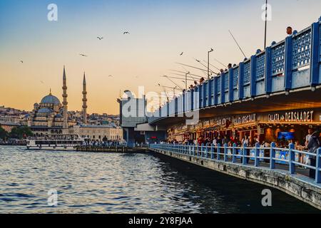 Türkiye. Istanbul. Sonnenuntergang über der Galata-Brücke in Istanbul, mit Fischern entlang der Geländer und der majestätischen Yeni-Moschee in Istanbul Stockfoto