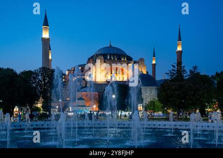 Turkiye. Istanbul. Die Hagia Sophia ist in der Abenddämmerung beleuchtet, mit einem Brunnen im Vordergrund, der die reiche Geschichte des ikonischen Gebäudes zeigt Stockfoto