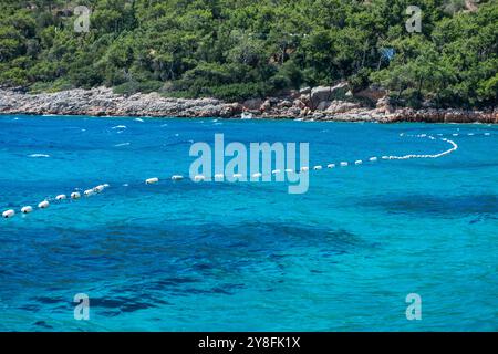 Eine schwimmende Pontonboje auf ruhigem blauem Meer bietet eine ruhige und friedliche Meereslandschaft mit lebhaften Farben und klaren Reflexen. Stockfoto