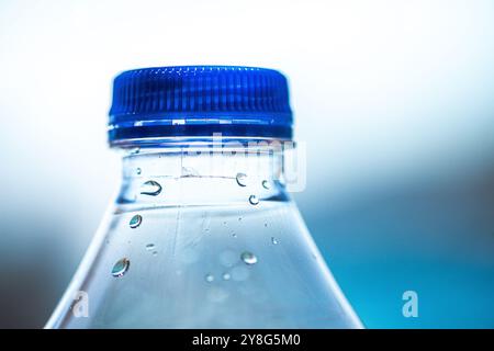 Eine Makroaufnahme einer Kunststoffflasche, die mit glitzernden Wassertropfen bedeckt ist und die Textur- und Kondensationseffekte hervorhebt. Stockfoto