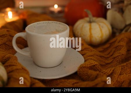 Tasse Kaffee auf weichem Pullover, Nahaufnahme. Herbstatmosphäre Stockfoto