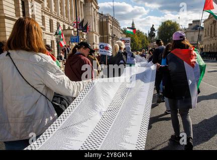 London, Großbritannien. Oktober 2024. Eltern und Kinder führen eine lange Liste der Namen der palästinensischen Kinder, die bisher im Gaza-Konflikt getötet wurden. März für Palästina. Anhänger Palästinas marschieren für ein Ende des Krieges in Gaza. Schätzungen zufolge wurden in Gaza rund 41.000 Menschen getötet, davon etwa die Hälfte Kinder. Die fordern einen sofortigen Waffenstillstand und ein Ende der Angriffe auf den Libanon. Die israelische Gegendemonstration fordert die sofortige Freilassung der Geiseln nach dem Massaker am 7. Oktober. Quelle: Karl Black/Alamy Live News Stockfoto